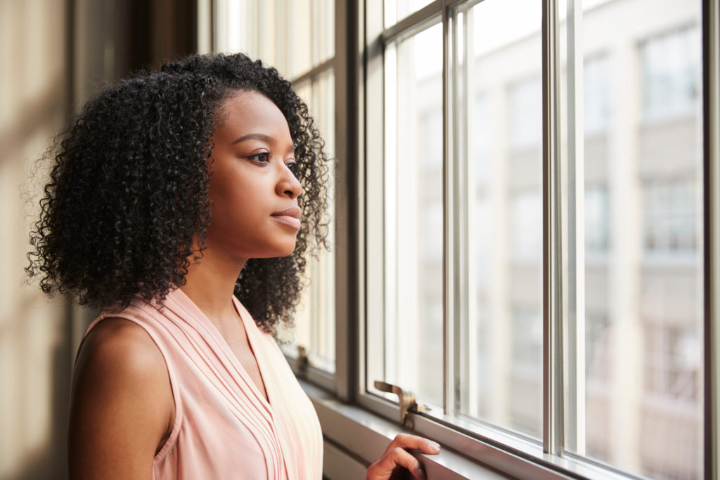 Young black woman looking out of window